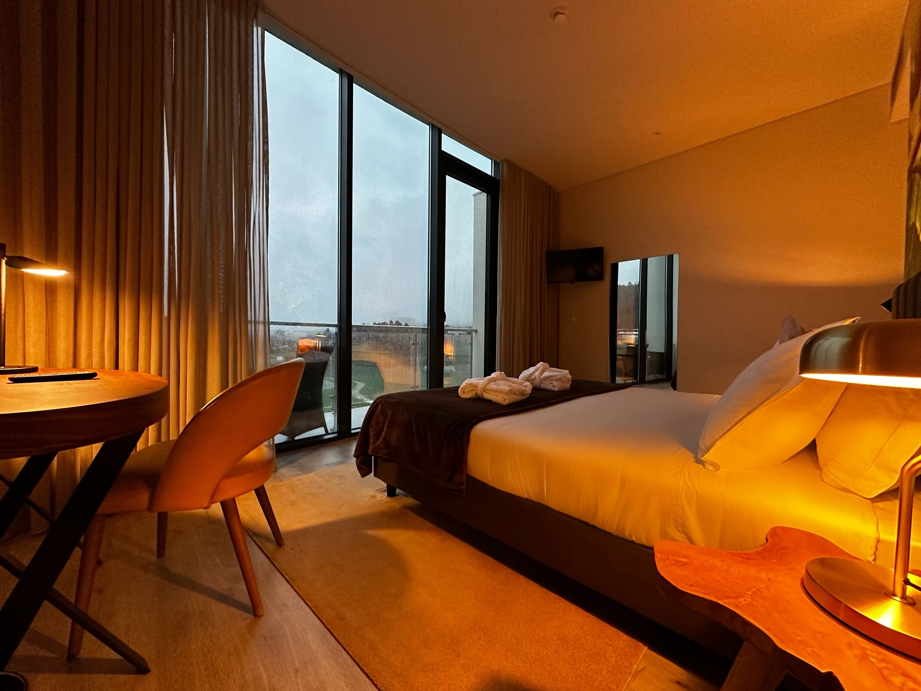 Une chambre d’hôtel avec un grand lit, un bureau, une chaise et une vue par la fenêtre.
