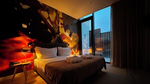 A modern hotel room with a large bed, a nightstand, a lamp, and a view of the outside. - Grapple Hotel (Carrazeda de Ansiaes)