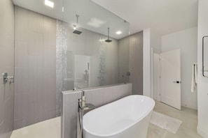 A modern bathroom with a freestanding bathtub, a glass-enclosed shower, and a large mirror.