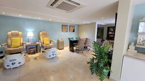 A room with massage chairs, a desk, and a small table with a plant.
