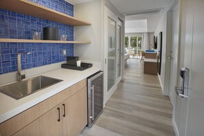 A modern kitchen with a stainless steel sink, wooden cabinets, and blue-tiled backsplash.