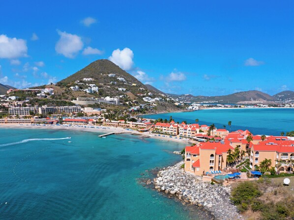 Une station balnéaire dotée de villas en bord de mer, avec une chaîne de montagnes en toile de fond et des eaux turquoise cristallines.