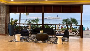 Ein großzügiger Lounge-Bereich mit großem Fenster zum Meer, ausgestattet mit einer modernen Sofagarnitur, einem runden Couchtisch und einer dekorativen Vase.