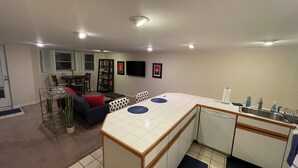 Una cocina compacta con zona de comedor, una pequeña estantería y un televisor en la pared.
