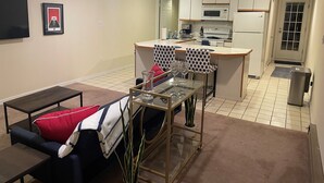 Un espacio habitable compacto con sofá, una pequeña mesa de comedor y una zona de kitchenette.