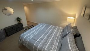 Un dormitorio con cama, cómoda, espejo y lámpara.