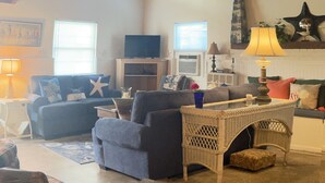 A living room with a sofa, a wicker table, and a television. - The Sea Witch-Beautiful inlet views just one block from beach! (Murrells Inlet)