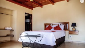 Un dormitorio con una cama, una mesita de noche, una lámpara y una pequeña mesa con una silla.