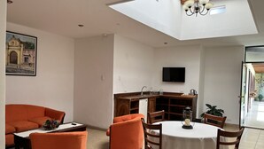 Un espacio habitable compacto con comedor, cocina y un amplio ventanal.