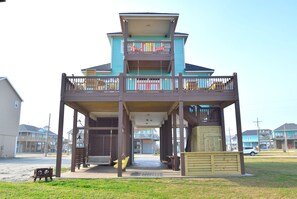 A two-story building with a balcony, a covered porch, and a swing set.