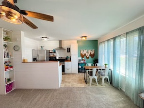 A compact kitchen with a central island, a dining area with a table and chairs, and a ceiling fan.