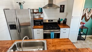 Een moderne keuken met roestvrijstalen apparatuur, een houten aanrechtblad en een inbouwoven.