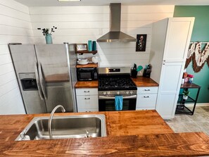 A modern kitchen with stainless steel appliances, a wooden countertop, and a built-in oven.