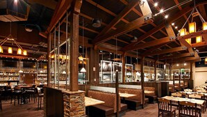 Un restaurante con vigas de madera, pilares de piedra y una zona de bar.