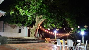 An outdoor patio area with a tiled floor, white plastic chairs, and a table.
