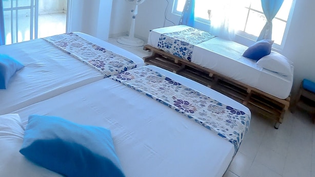 A room with two beds, a TV, a fan, and a balcony.