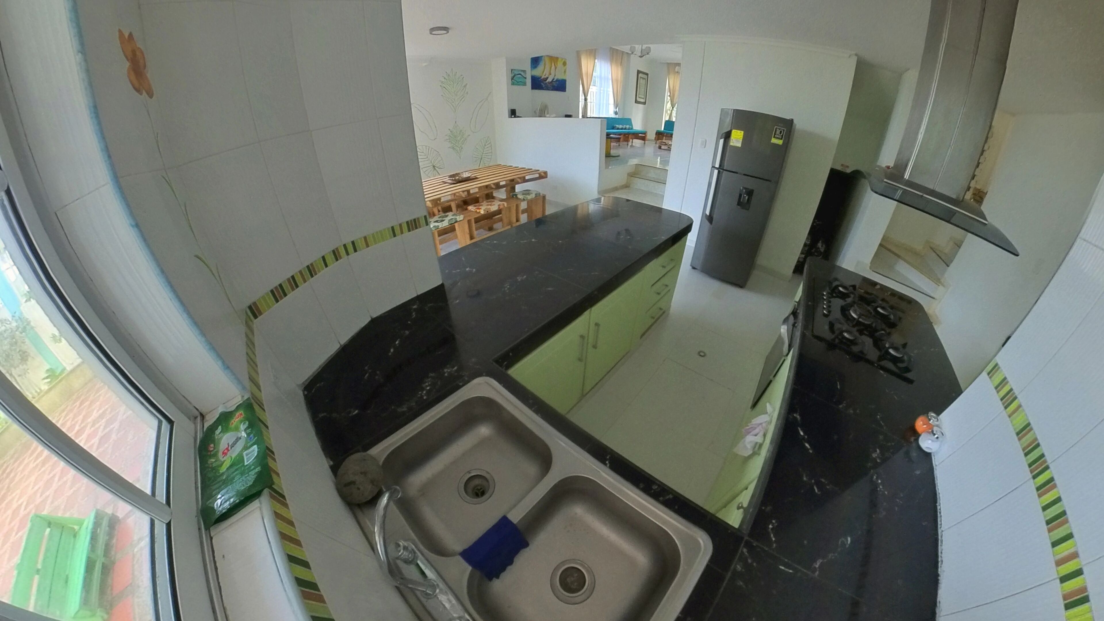 Een keuken met een dubbele spoelbak, een koelkast en een fornuis.