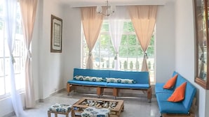 A spacious living room with a blue sofa, a wooden coffee table, and a chandelier.