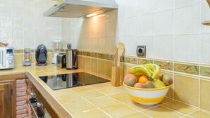 Ett kök med en gasspis, en brödrost och en skål med frukt på bänkskivan.