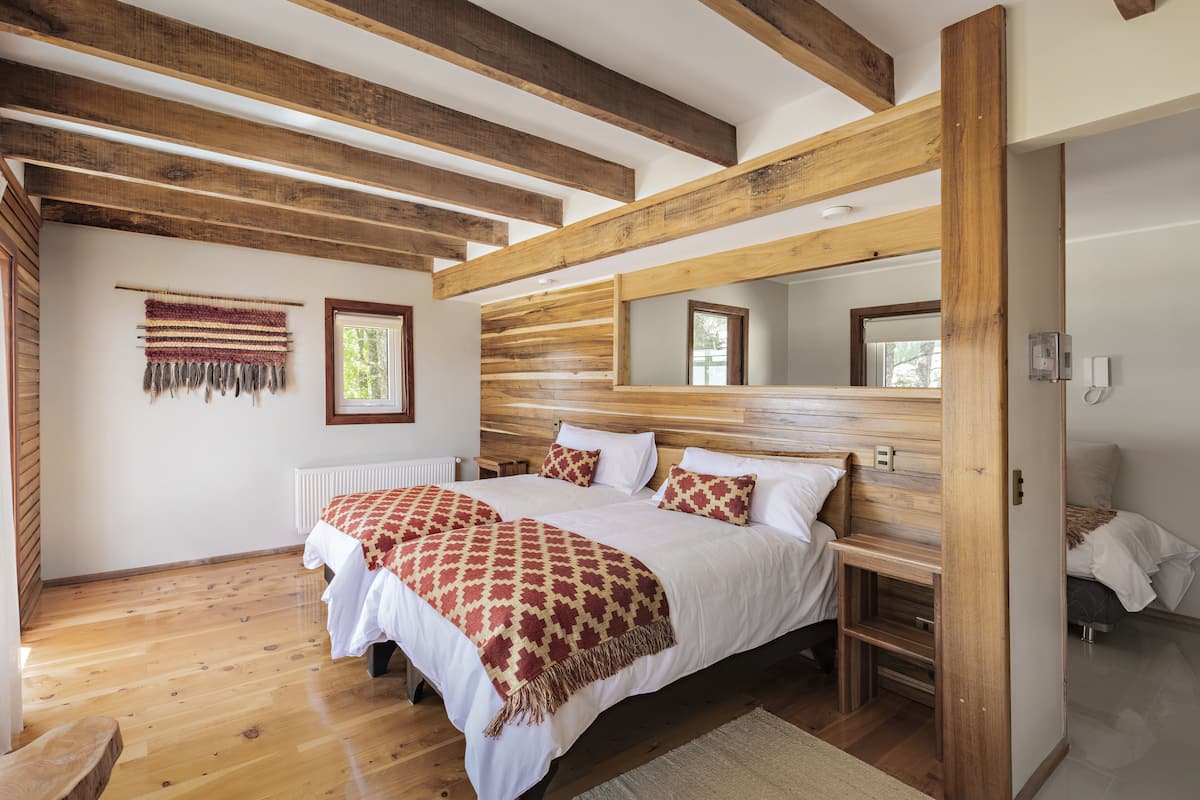 Un dormitorio con una cama grande, vigas de madera, un espejo y una ventana.