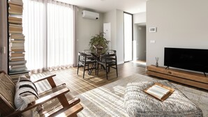 Una sala de estar moderna con un sofá, una mesa de centro, un televisor y un comedor con una mesa y sillas.