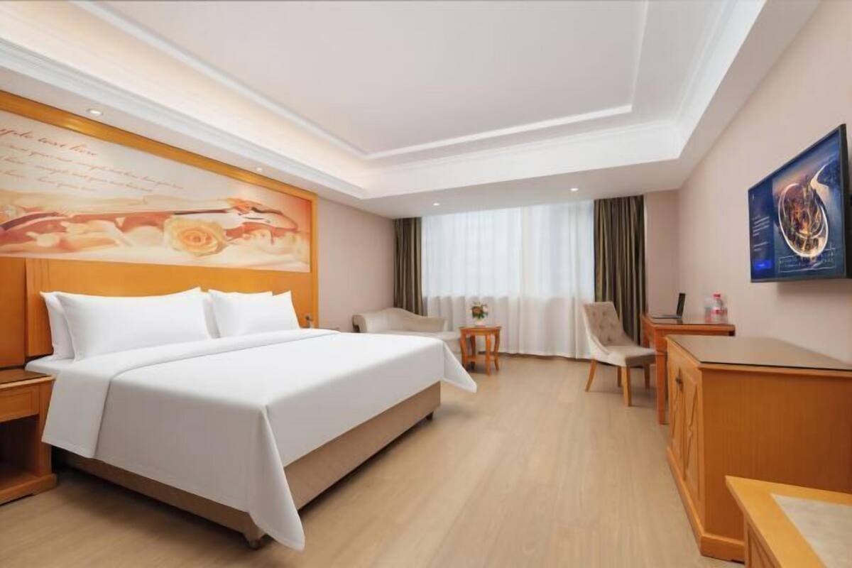 Una habitación de hotel con una cama grande, un escritorio, una silla y una mesita.