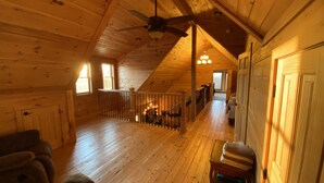 Amplia habitación estilo loft con pisos de madera, techo inclinado y balcón.