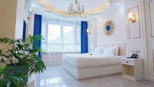 A hotel room with a bed, bedside table, and a potted plant. - Hongji Business Hotel (Fujin)