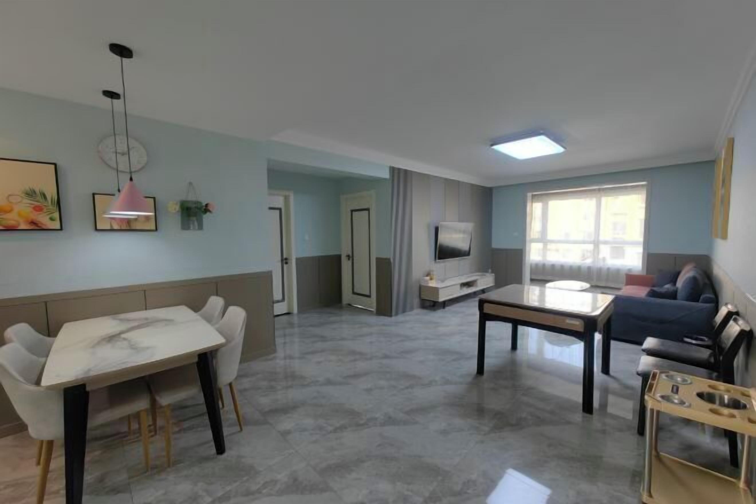 Una sala moderna con comedor, televisor y sofá.