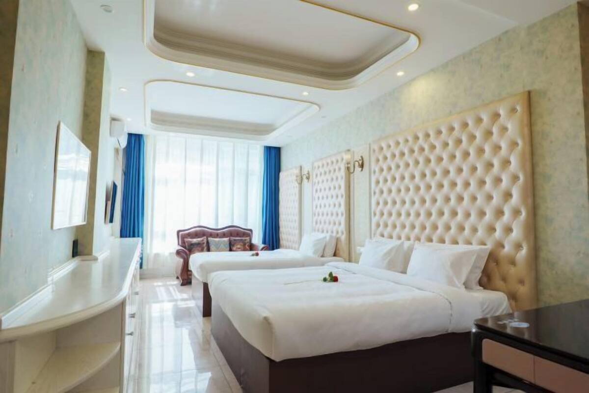 Habitación de hotel con dos camas, un ventanal grande, una bañera y un tocador.