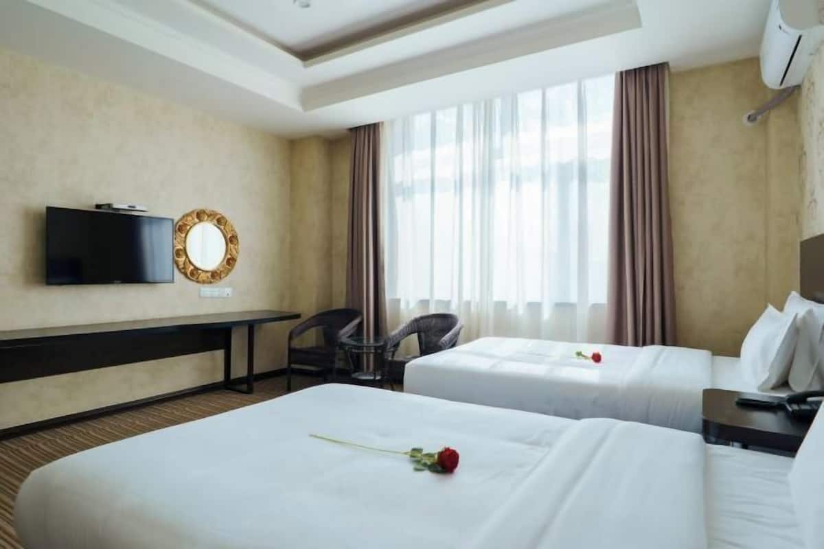 Habitación de hotel con dos camas, televisión, escritorio y un amplio ventanal con cortinas.