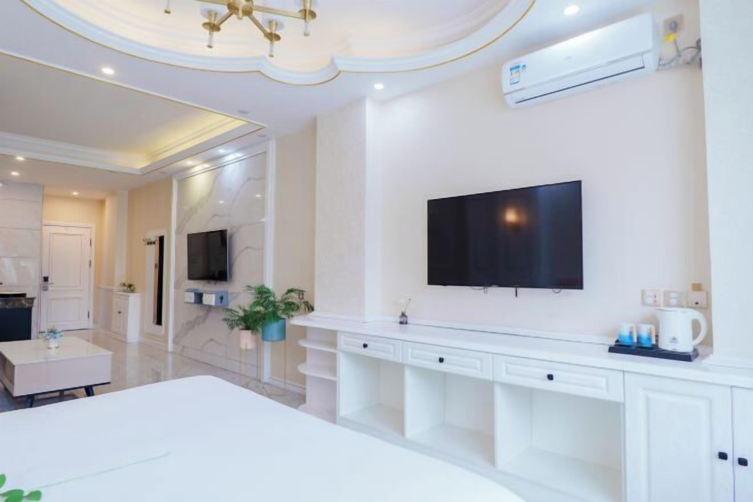 Une chambre d’hôtel moderne dotée d’un grand lit, d’un téléviseur fixé au mur, d’une console blanche et d’une douche intégrée.