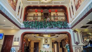 A grand lobby with a central staircase, a chandelier, and a balcony with red lanterns. - Hongji Business Hotel (Fujin)