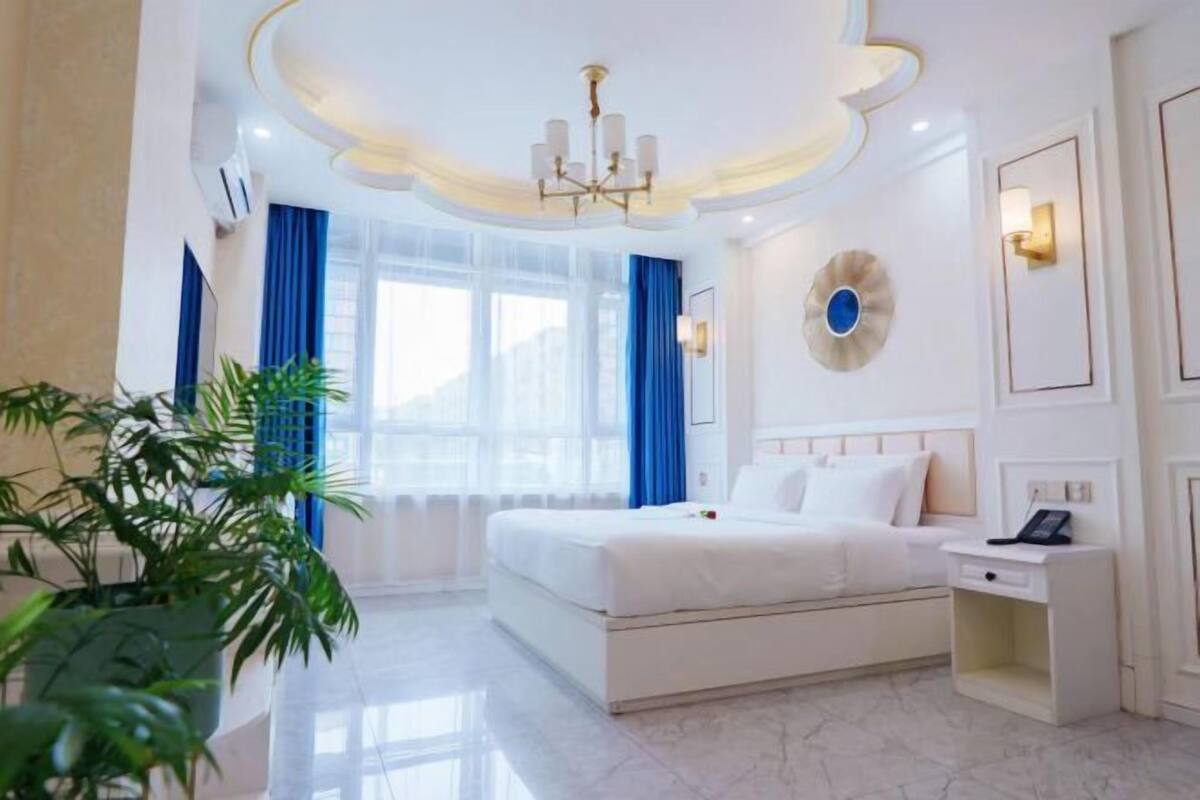 Una habitación de hotel con cama, mesita de noche y lámpara de pared.