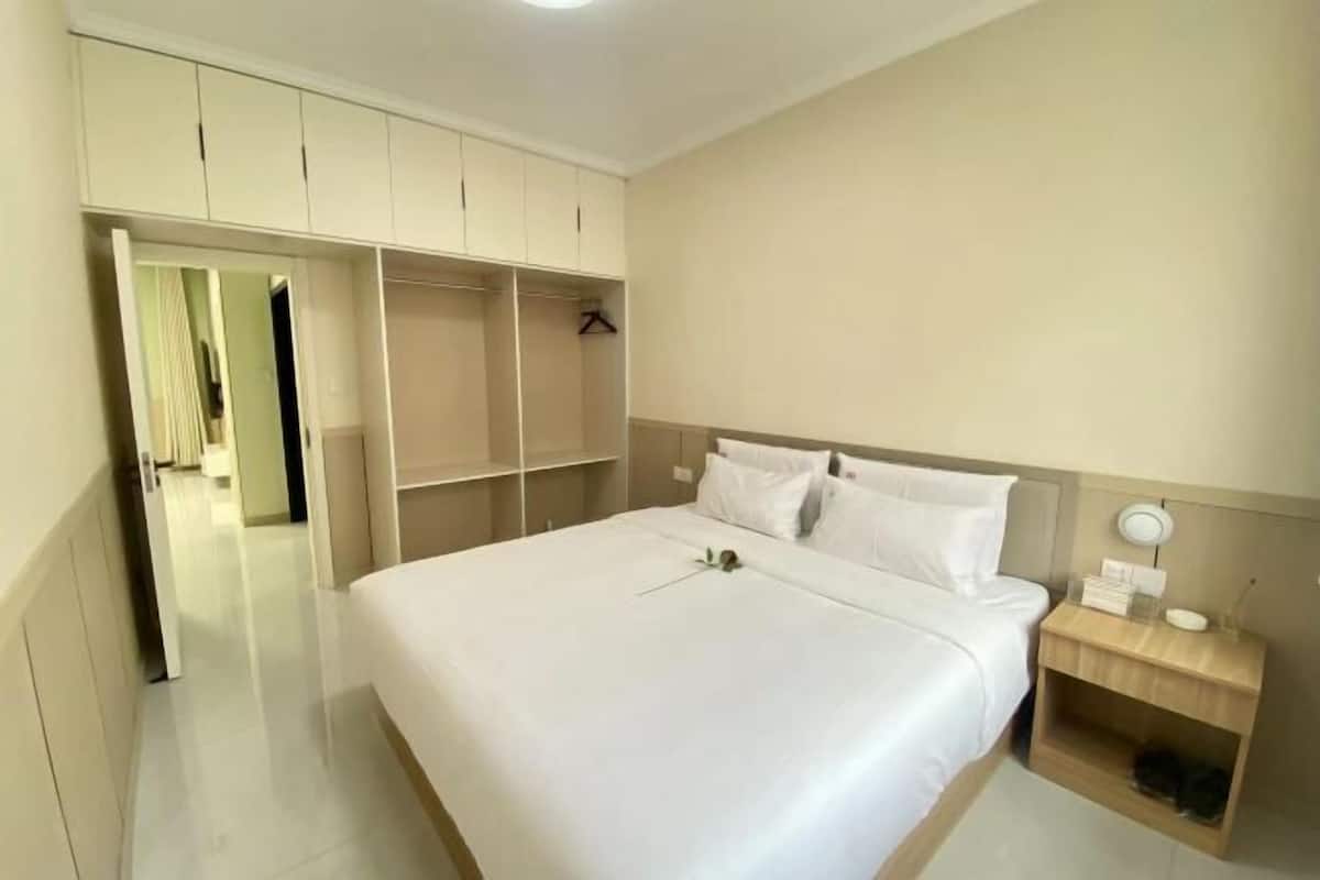 Un dormitorio con cama, mesita de noche, armario y espejo.