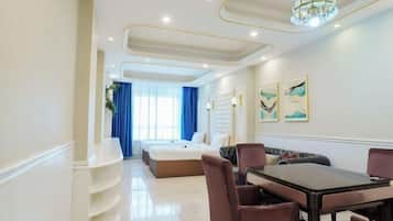 A hotel room with a bed, a dining table with chairs, a chandelier, and artwork on the wall.