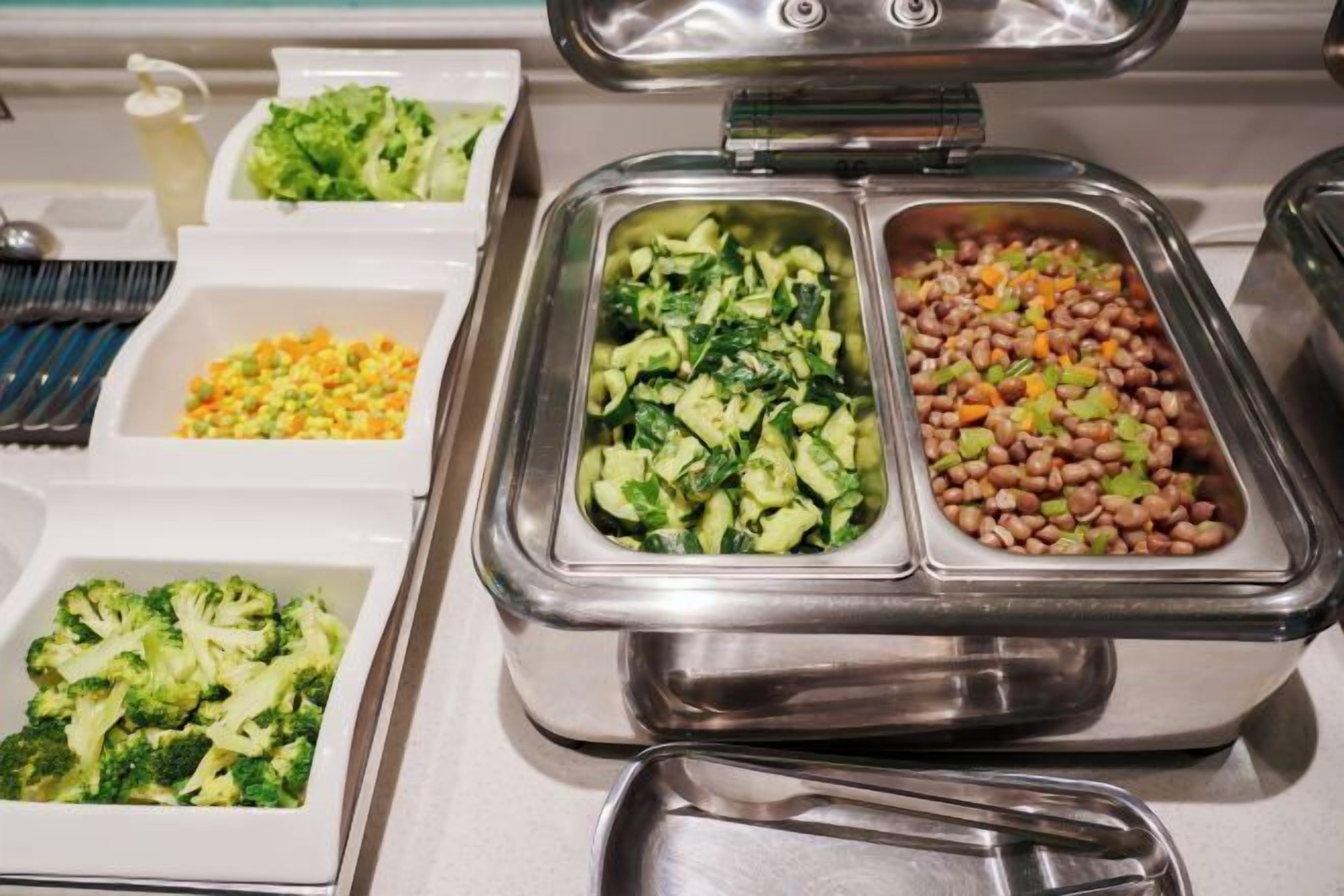 A buffet with various food options including broccoli, mixed vegetables, and beans.