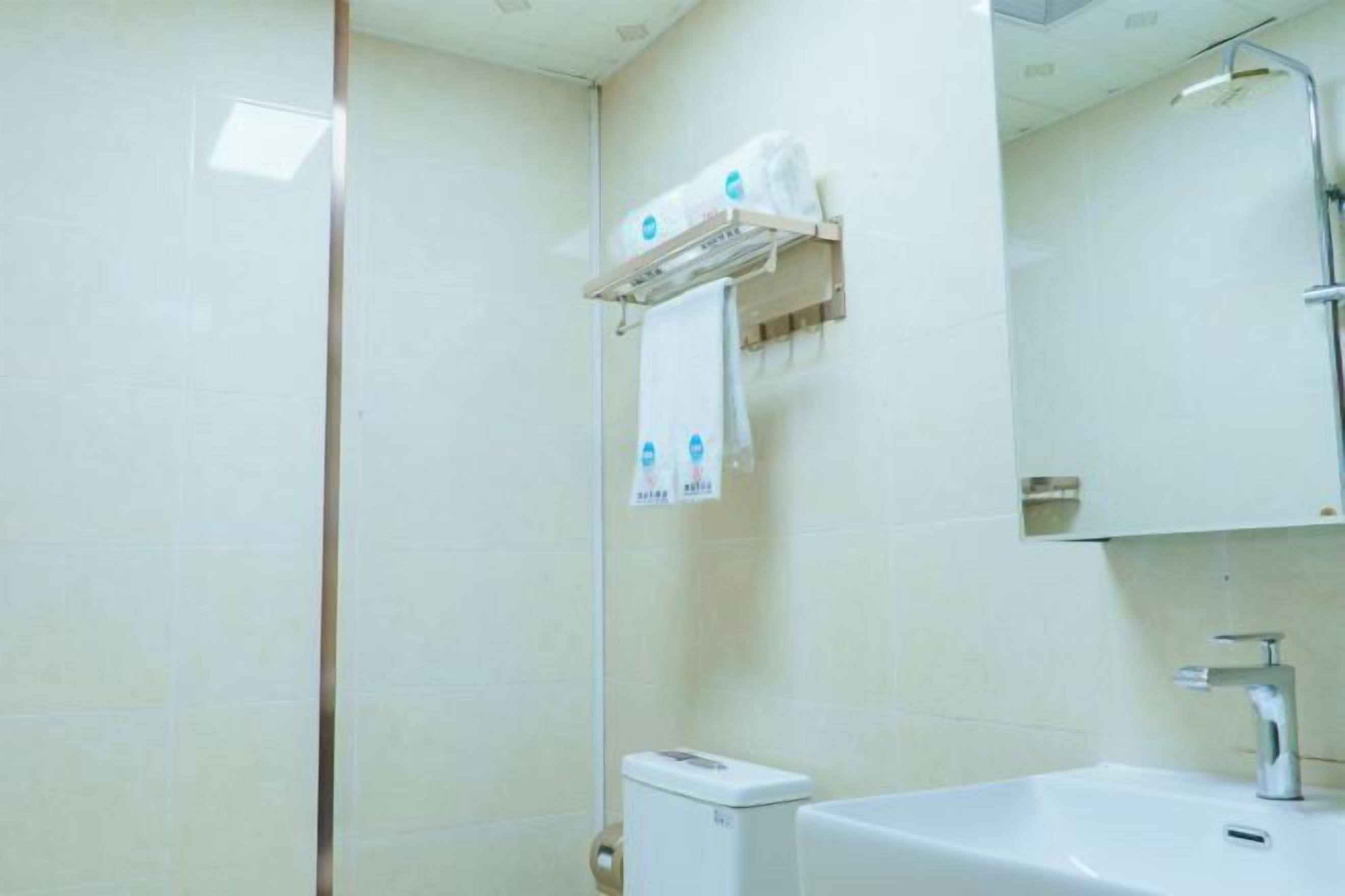 A bathroom with a toilet, a sink, a mirror, and a towel rack.