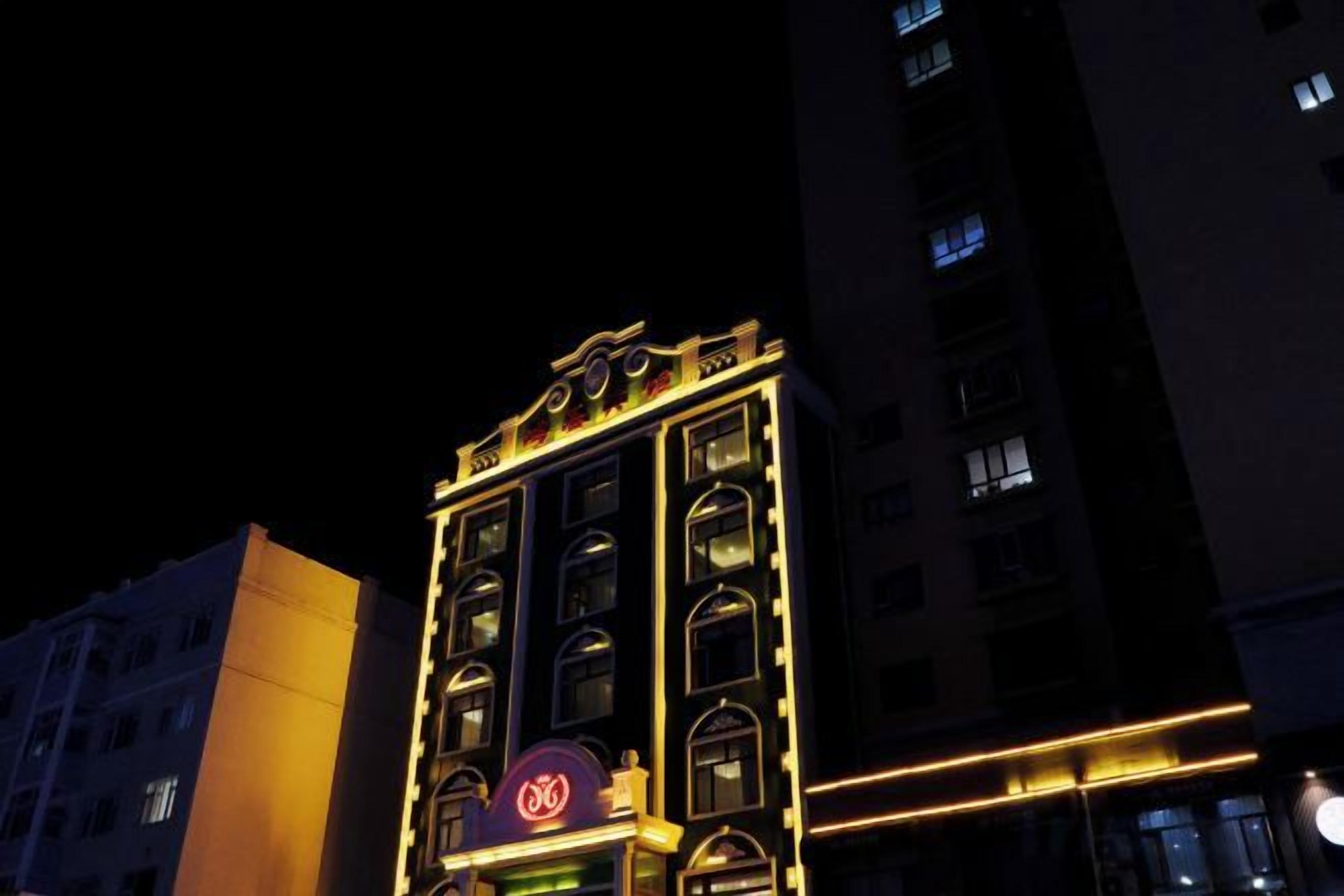 Un immeuble à plusieurs étages, doté d’une enseigne et de fenêtres illuminées, ce qui laisse supposer qu’il s’agit d’un bâtiment commercial ou d’un hôtel.