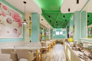 Un restaurante con una barra alargada, varias zonas de estar y un techo verde.