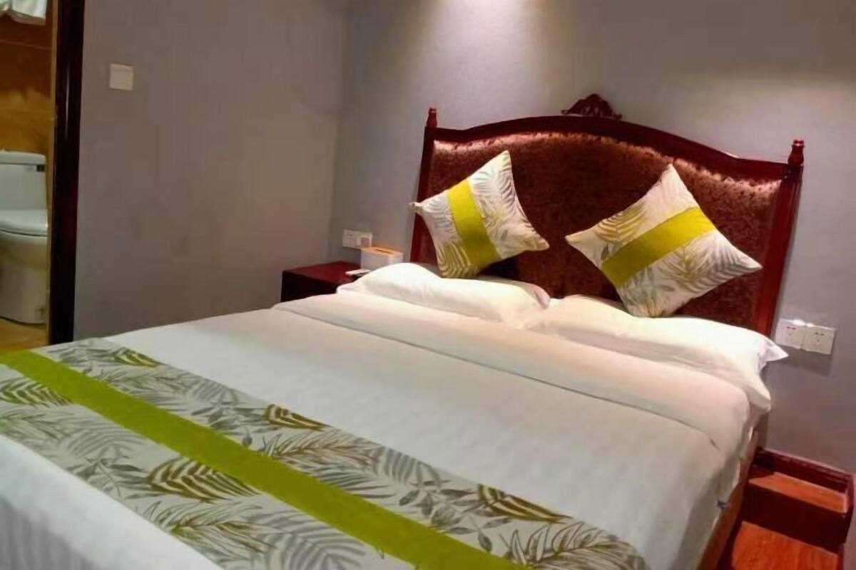 A hotel room with a bed, a wooden headboard, and a nightstand.