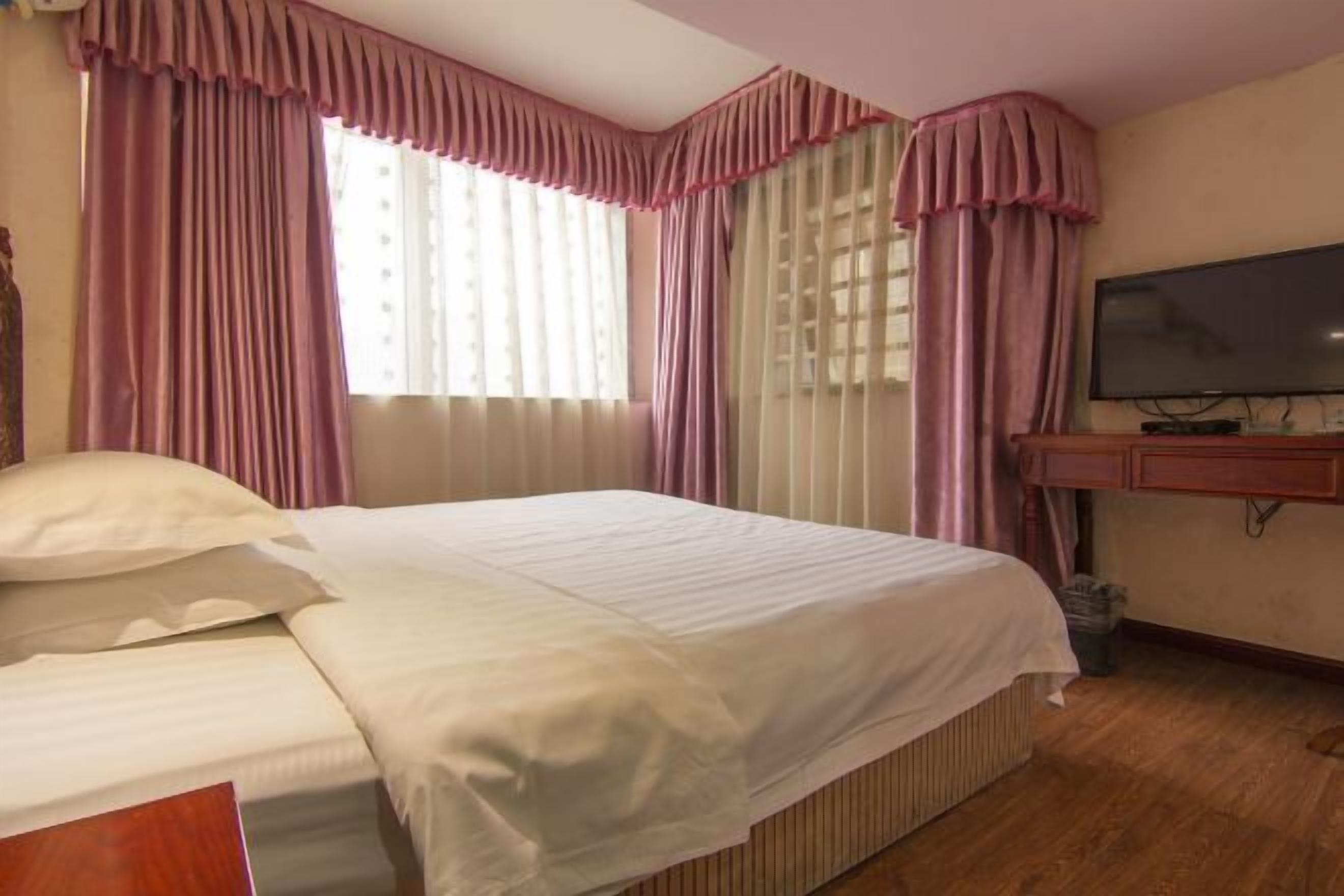 A hotel room with a bed, a television, and curtains.