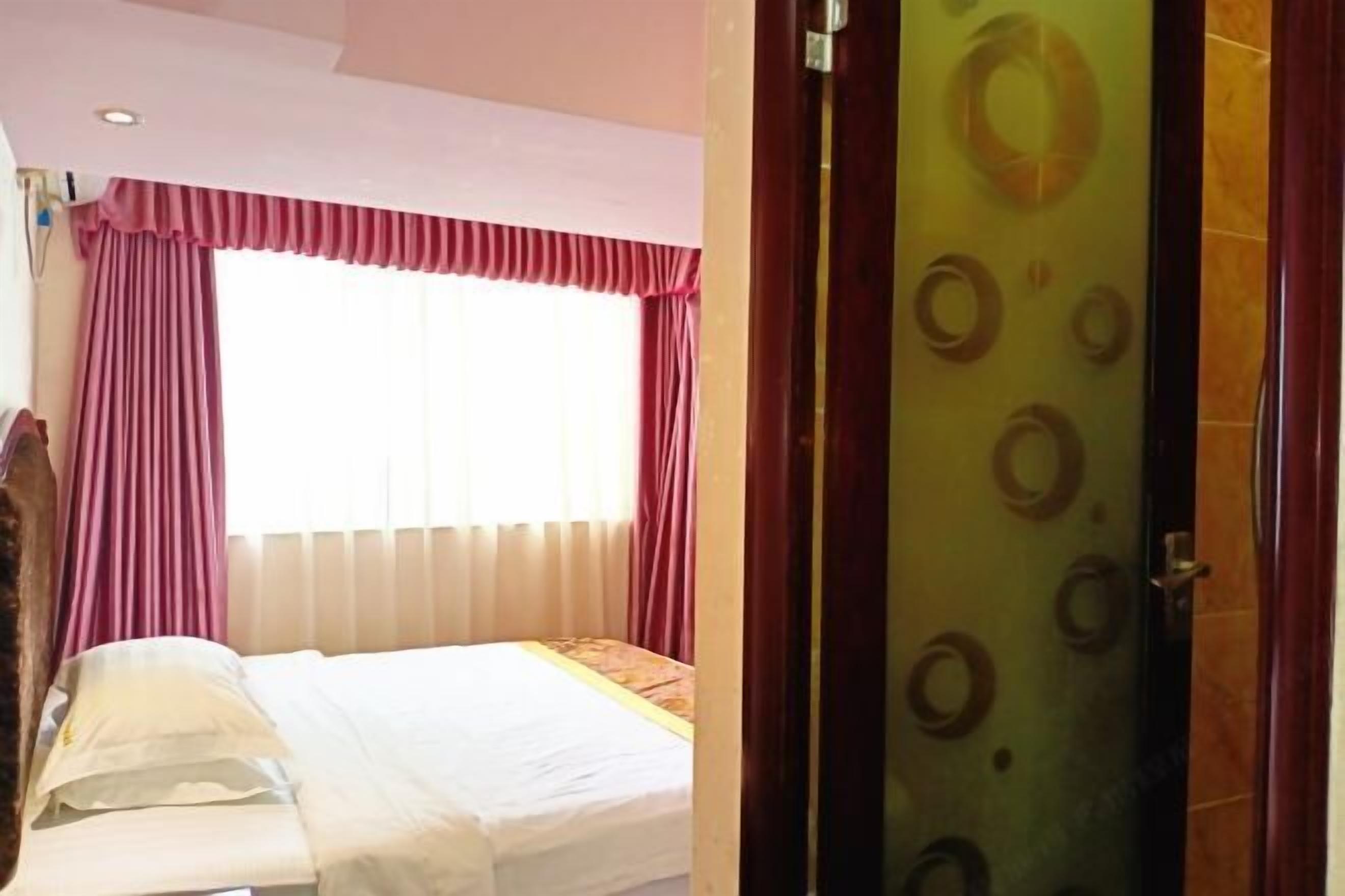 A hotel room with a bed, a window with curtains, and a door with a circular pattern.