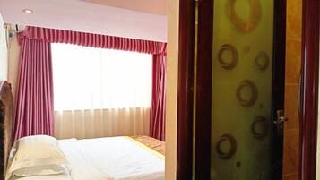 A hotel room with a bed, a window with curtains, and a door with a circular pattern.