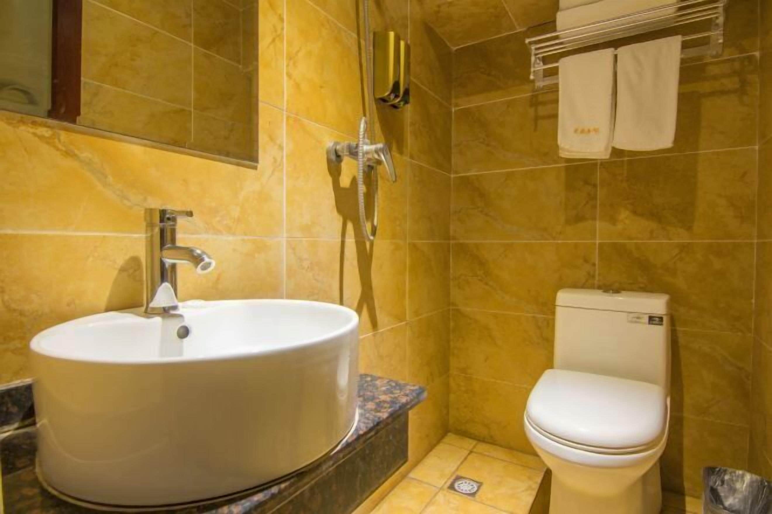 A bathroom with a round sink, a toilet, and a shower.
