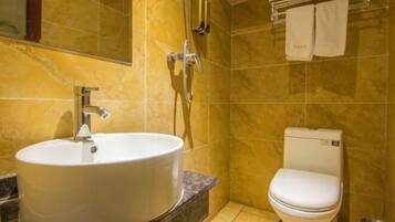 A bathroom with a round sink, a toilet, and a shower.