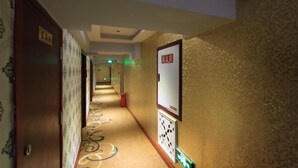 A hotel hallway with patterned carpet, a fire alarm, and a sign on the wall. - Yi Xiu Hotel (Chongqing)