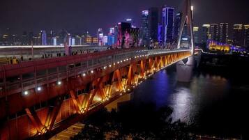 A nighttime cityscape with a prominent illuminated bridge and high-rise buildings.