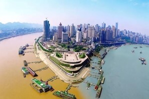 An aerial view of a waterfront city with high-rise buildings, a river, and a dock area. - Yi Xiu Hotel (Chongqing)