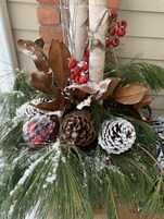 Un arreglo decorativo con ramas de pino, un abeto blanco, bayas rojas y piñones.